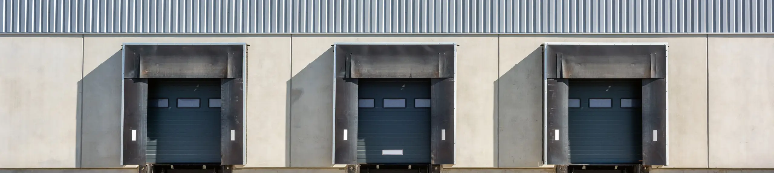Three loading bay doors on the outside of an industrial facility.