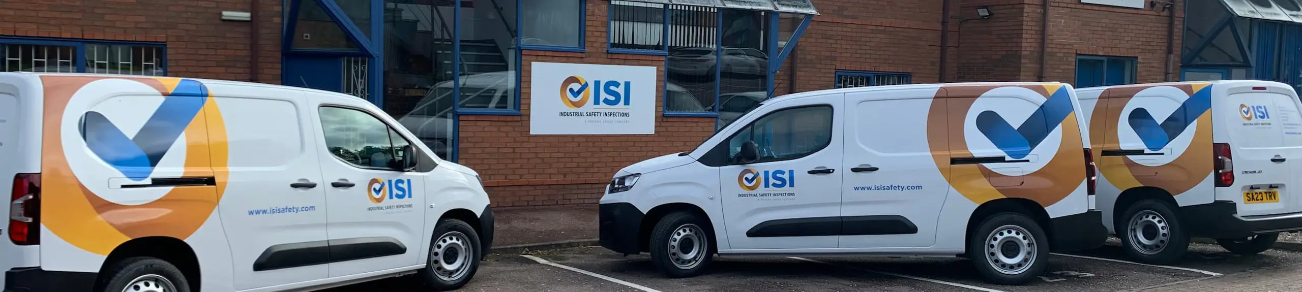 3 branded ISI vans parked outside office buildings